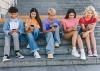 A group of teenagers sit on school steps with their phones