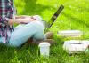 A person sits outside studying with laptop and books