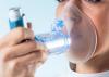 A woman manages her asthma with an inhaler featuring an extension tube for enhanced accessibility